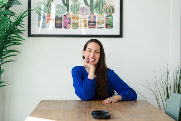 Vanessa Van Edwards at table with chin on hand smiling warmly