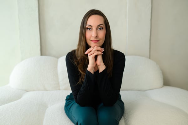 Vanessa Van Edwards seated on white sofa in composed pose