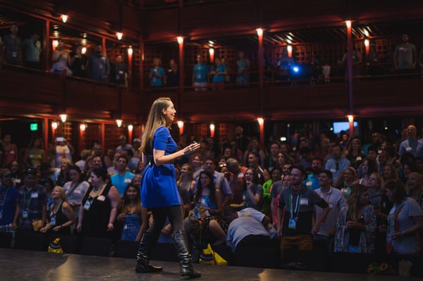 Vanessa Van Edwards speaking in historic theater in royal blue dress