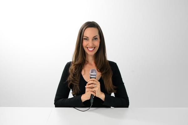 Vanessa Van Edwards holding microphone smiling in studio