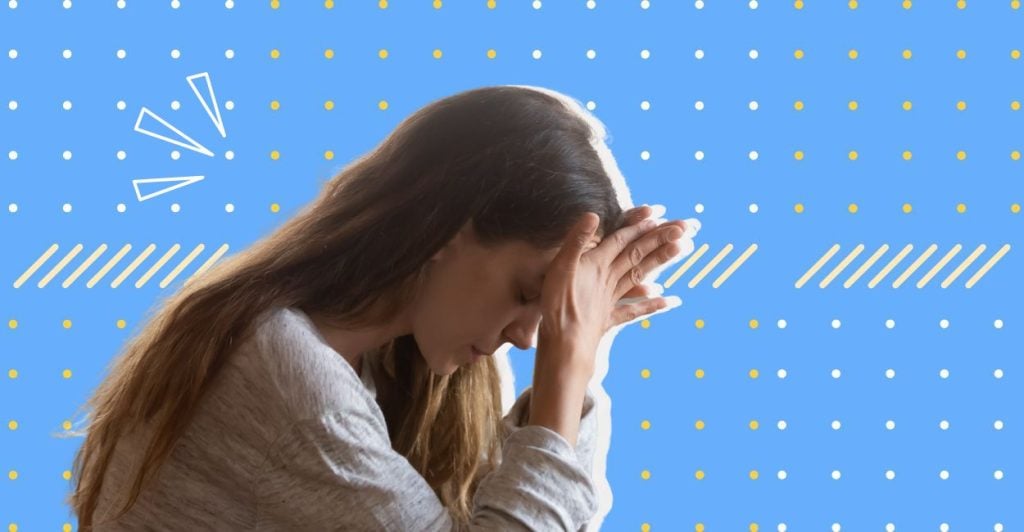 A woman with her hands on her forehead looking down. She appears to be really stressed. This relates to the article on choice paralysis.