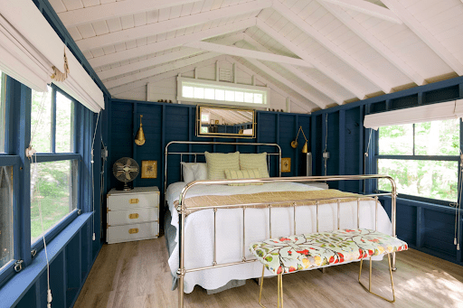 An image of a room with a large bed and dark blue walls, which is the visual representation of a study that found people who sleep in blue rooms get more sleep than in other colored rooms. This information comes from color psychology.