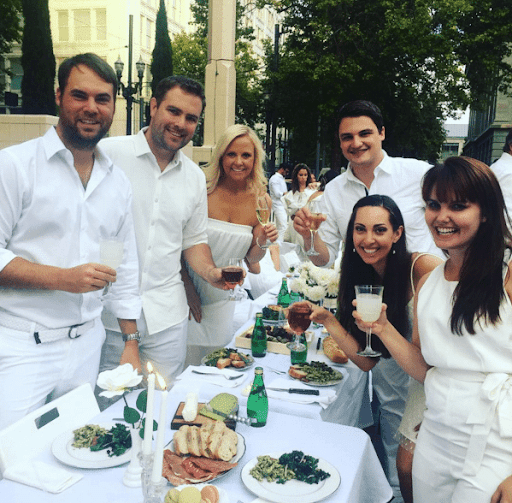 An image of Vanessa Van Edwards and all of her friends dressed in all-white having a picnic, which relates to the article on how to make friends as an adult.