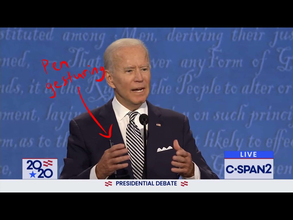 Biden gestures while holding a pen