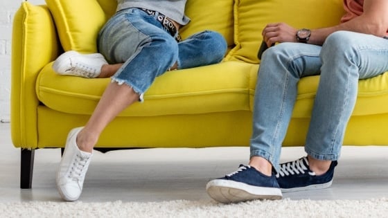 Woman sitting on the sofa near a man pointing her knees may point towards him