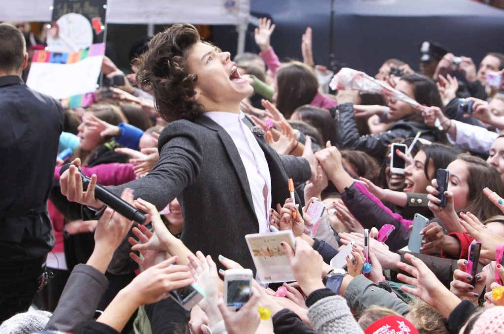 Crowd of fans reaching out celebrity's hands