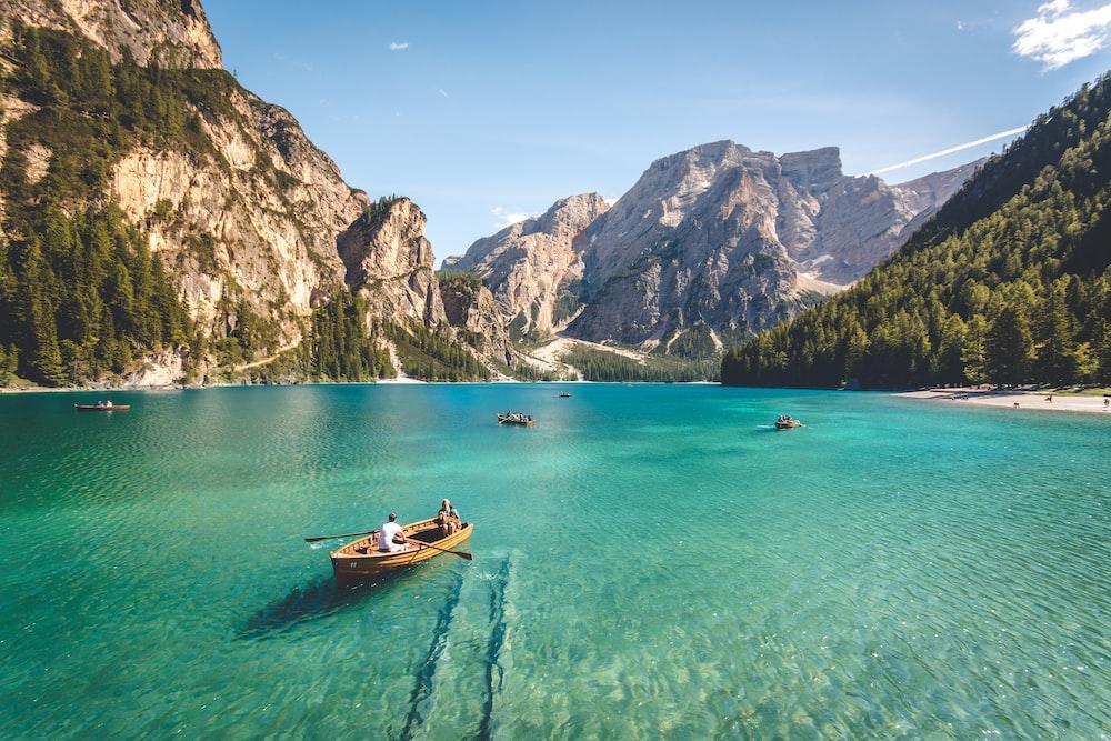 three brown wooden boats on blue lake water taken at daytime