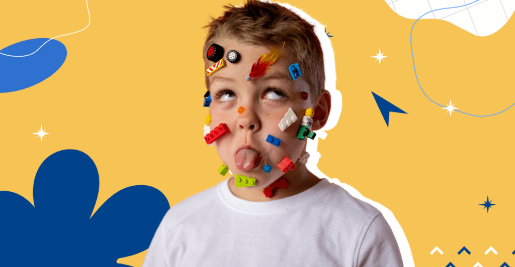 Boy sticking out his tongue with lego toys on his face