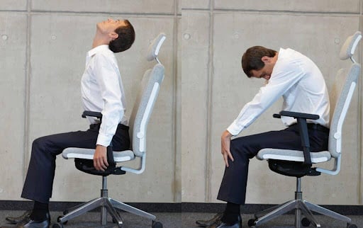 A man is at work doing a seated cat cow pose s an office exercise