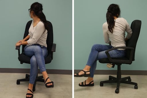 A woman is sitting in her office doing a chair twist as an office exercise