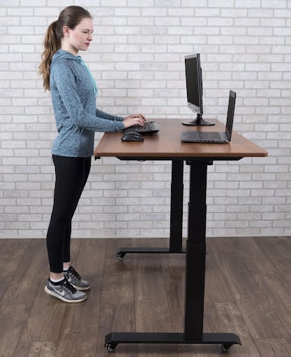 A women is at a standing desk doing calf raises as an office exercise