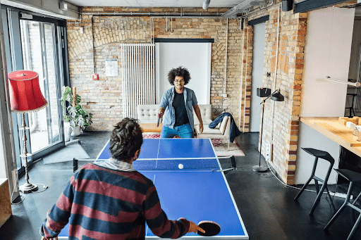 A fun break space with a ping pong table and two men playing as an office decor idea