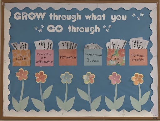 A bulletin board idea that says "grow through what you go through" with beautiful handmade flowers and the colorful envelope pockets.