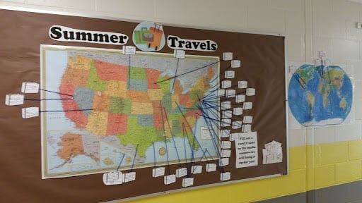 An image of a bulletin board idea with the title "summer travels" with a map as the background. There is also string attached by a pushpin coming from a point on the map to the outside of the map, with something about travels written on them. Another option could be to attach photographs.  